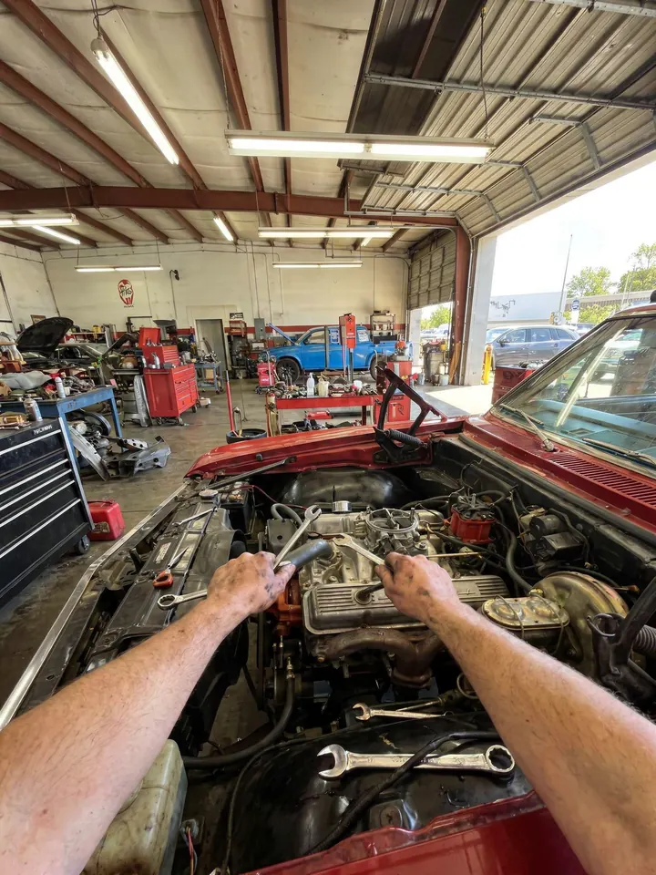 Hands working on a car engine in an auto shop